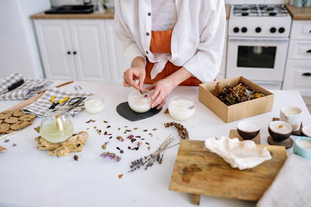 An artisan creates handcrafted candles using dried flowers in a cozy workshop.