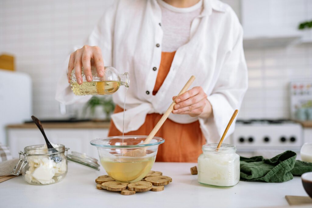 Woman crafting homemade soy candles using natural ingredients in kitchen.